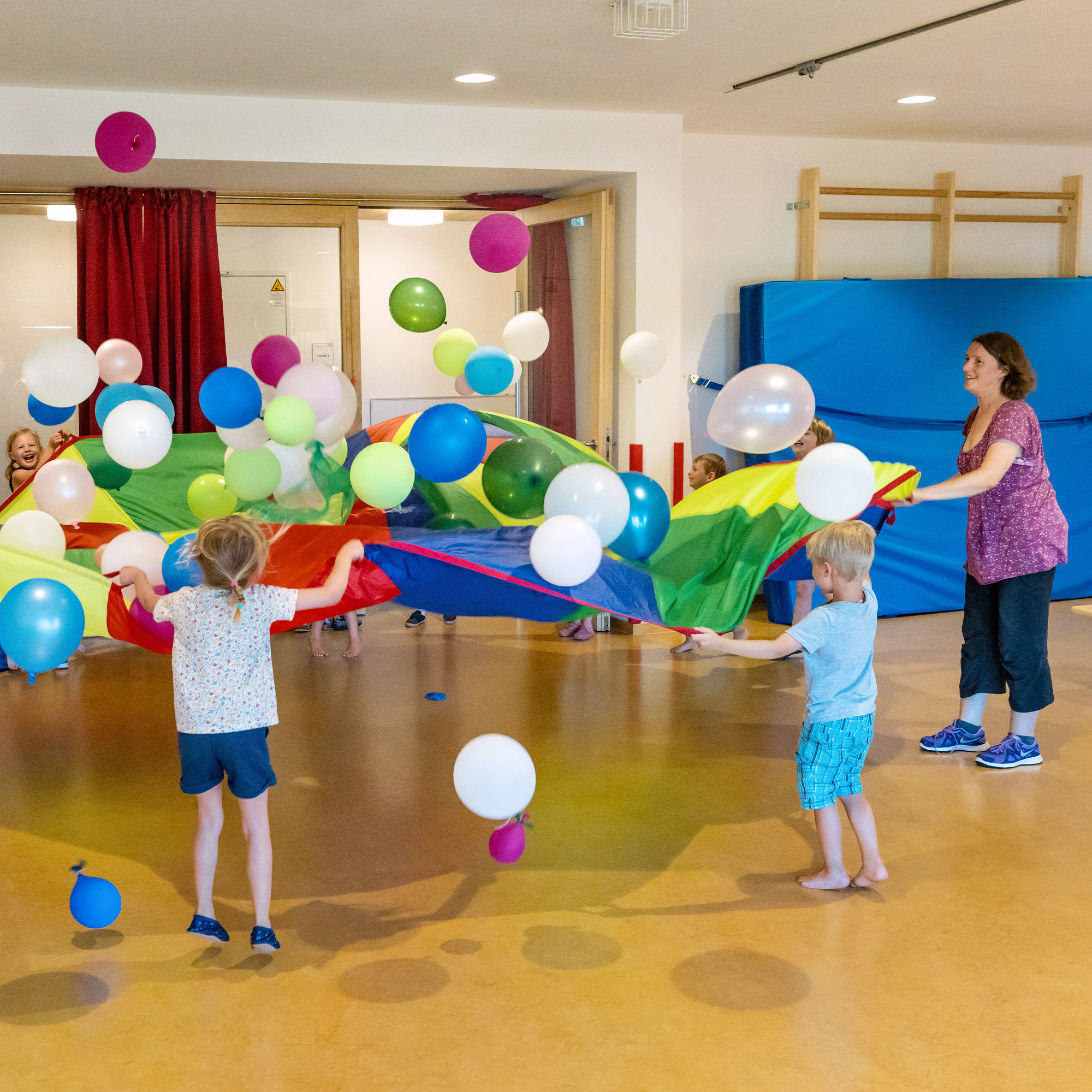 Eine Betreuerin der SGA Sport-Kita spielt gemeinsam mit Kindern mit Luftballons.