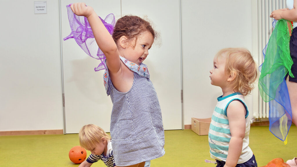 Die Kinder der SGA Sport-Kita spielen zusammen mit Tüchern.