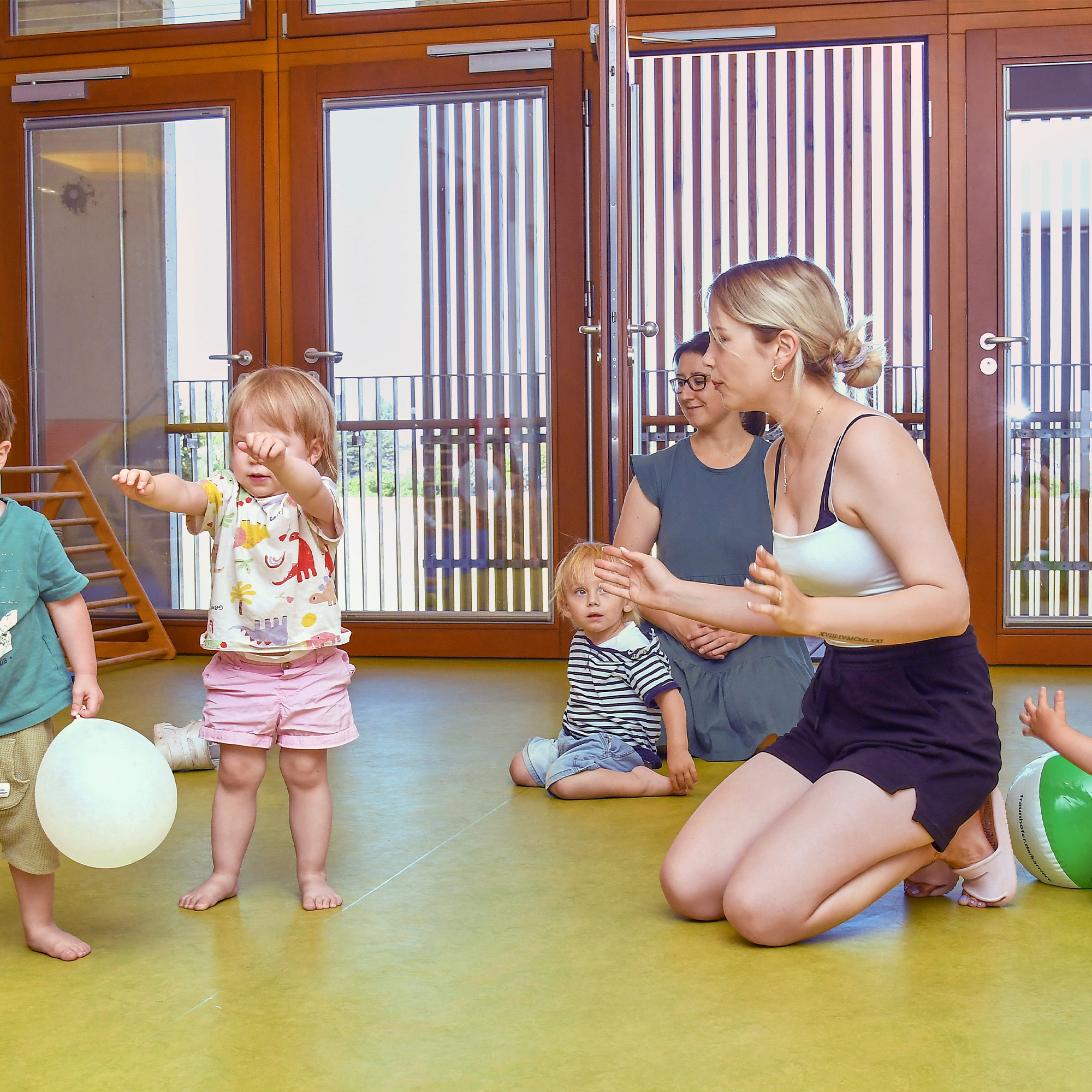 Die Betreuer der SGA Sport-Kita spielen gemeinsam mit den Kindern mit Luftballons.