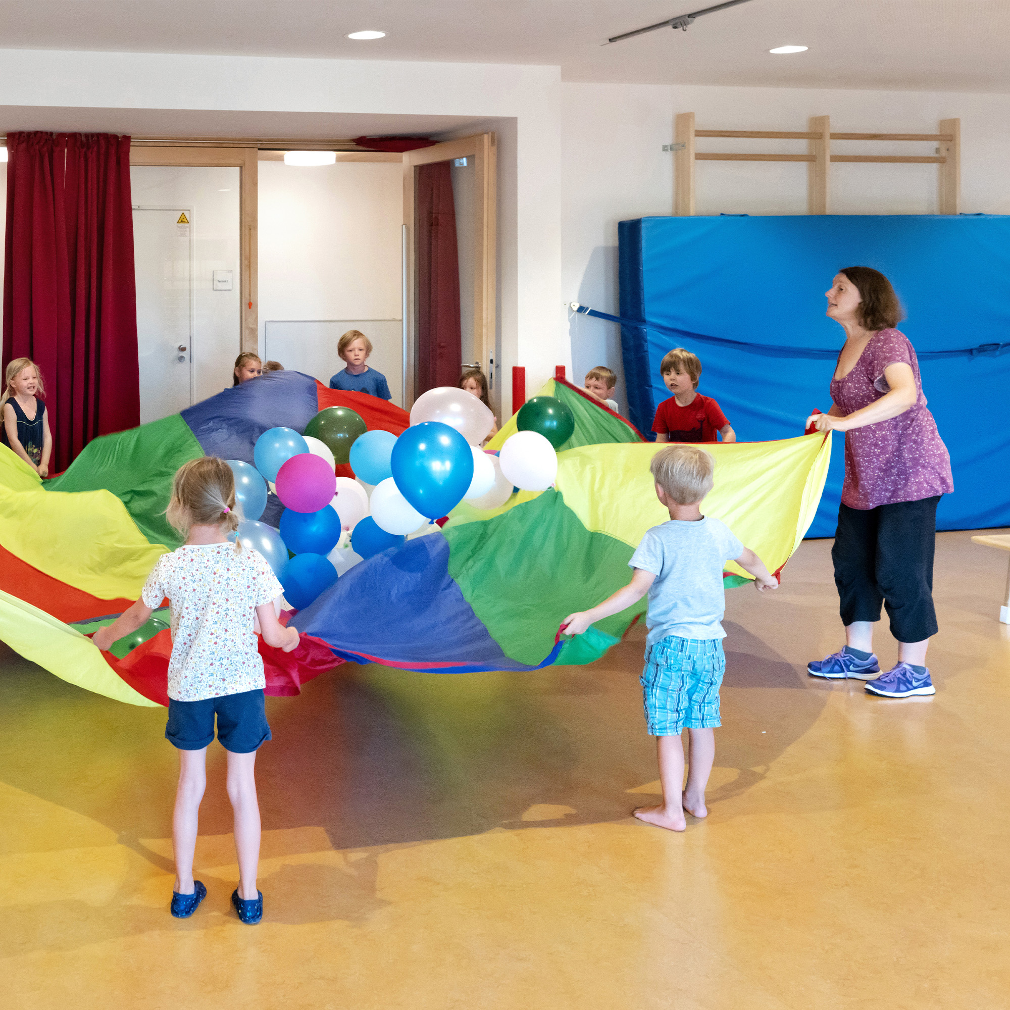 Eine Betreuerin der SGA Sport-Kita spielt gemeinsam mit Kindern mit Luftballons.