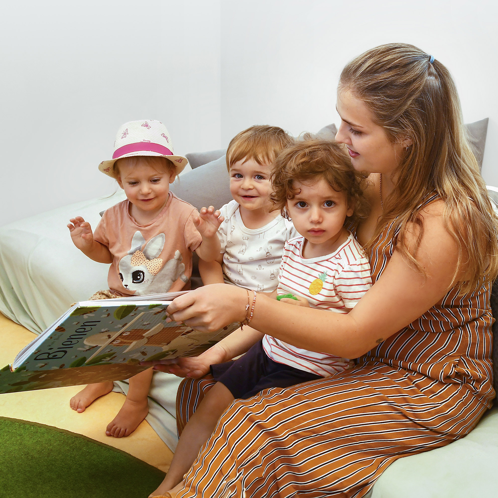 Eine Betreuerin der SGA Sport-Kita liest mehreren Kindern etwas aus einem Kinderbuch vor.