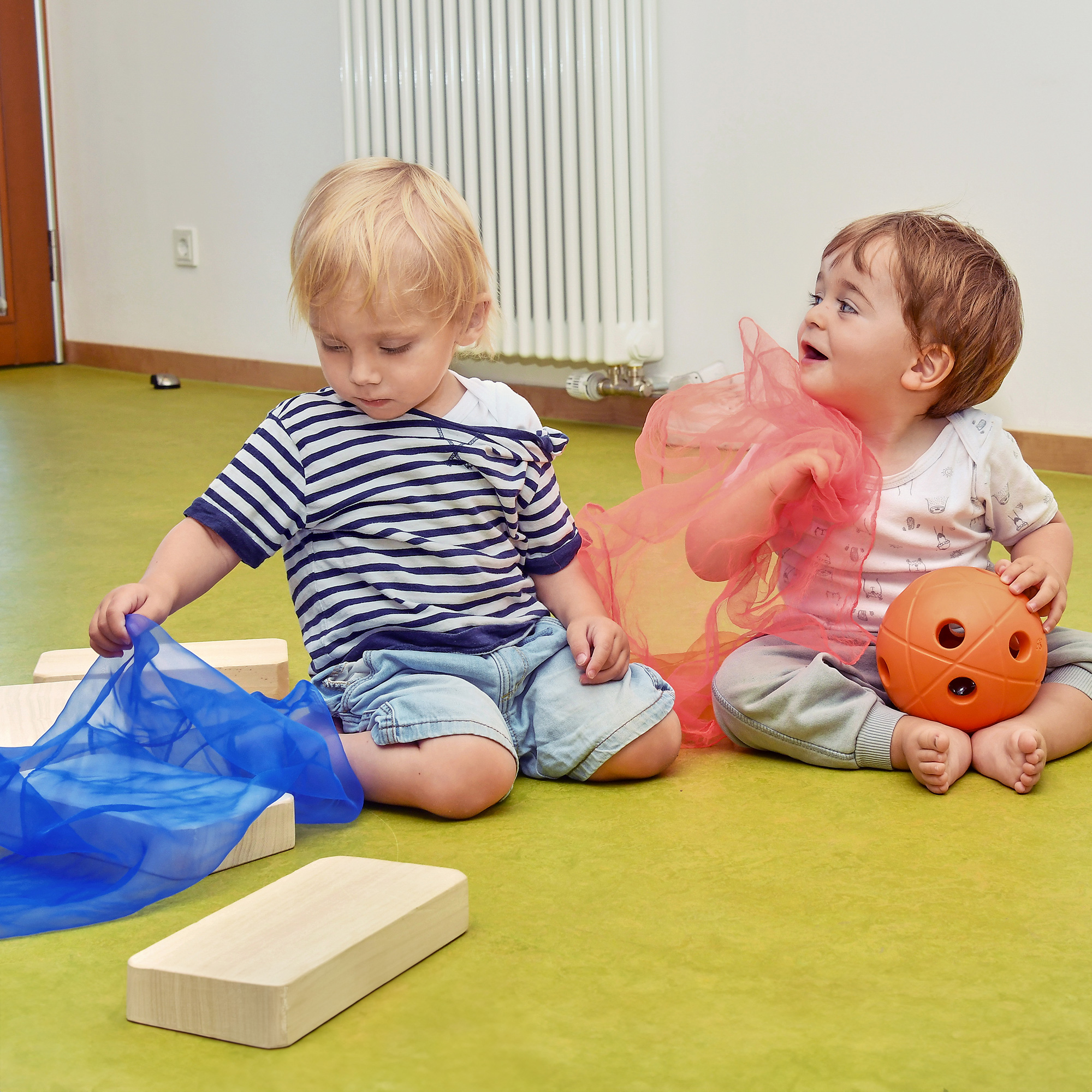 Die Kinder der SGA Sport-Kita spielen zusammen mit Tüchern und einem Ball.